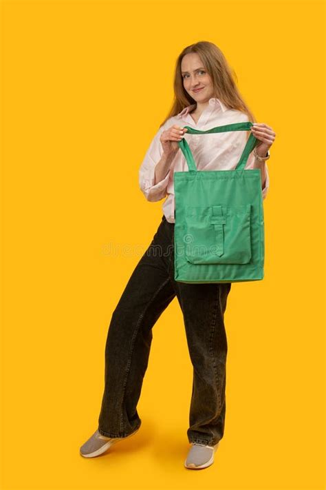 Beautiful Young Woman with Green Shopping Bags Stands Against Yellow ... 