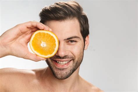 Photo Of Cheerful Half Naked Man Smiling And Holding Orange Stock Image