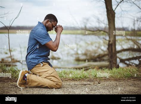 Vertical Shot Of An African American Male Praying On His Knees Stock