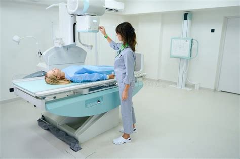 Qualified Radiologic Technologist Preparing Woman For Radiography Stock