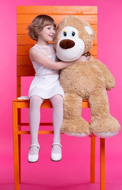 Niña con un oso sentado en una silla Foto Premium