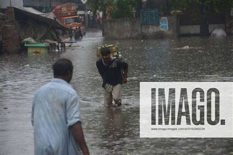 Pakistani Commuters Wade Through A Flooded Street At Baghban Pura Area