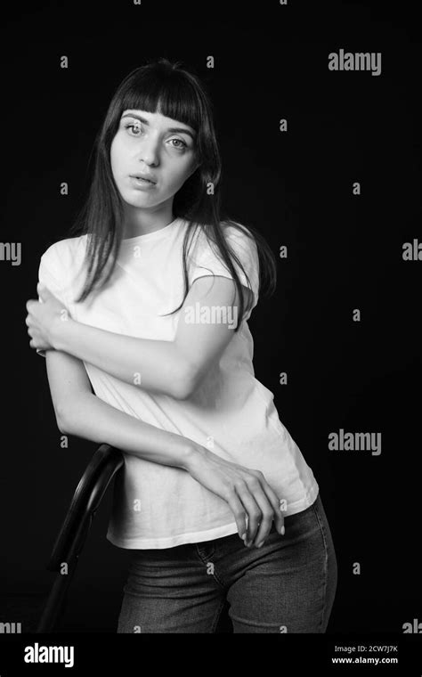 Studio Portrait Of A Pretty Brunette Woman In A White Blank T Shirt Against A Plain Black