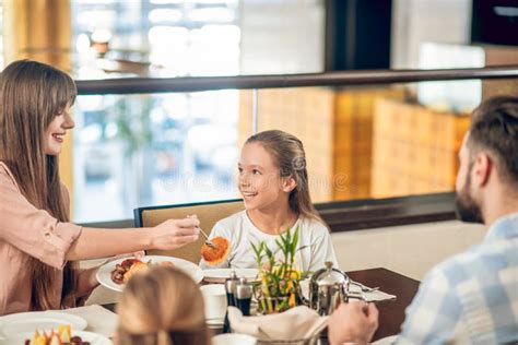 Familia Feliz Sentada En La Mesa Servida Y Luciendo Alegre Foto De