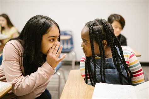 2 Students Whispering To Each Other In Class