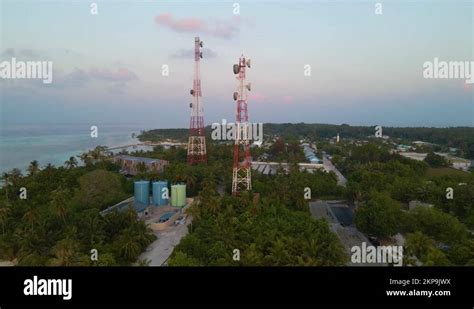 Two cell towers surrounded by green trees and buildings on the shores ...