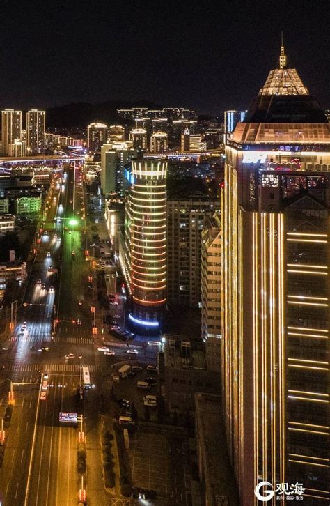 An Aerial View Of A City At Night With Traffic And Buildings In The