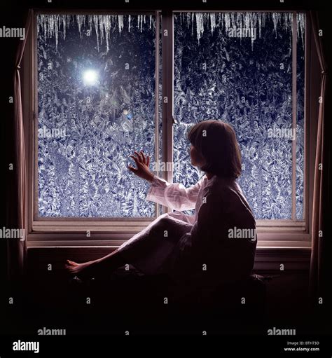 Young Girl Looking Looking Out Window At Star During The Holiday Stock