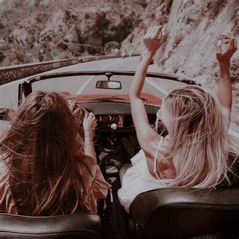 Two Women Sitting In The Back Of A Convertible Car On A Road With