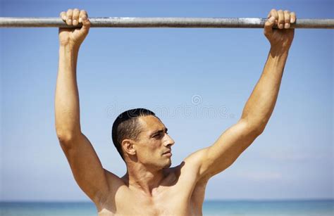A Male Athlete With A Naked Torso Is Training On A Horizontal Bar Stock