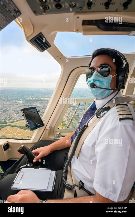 Vertical Portrait Of A Pilot Wearing A Face Mask Flying A Helicopter