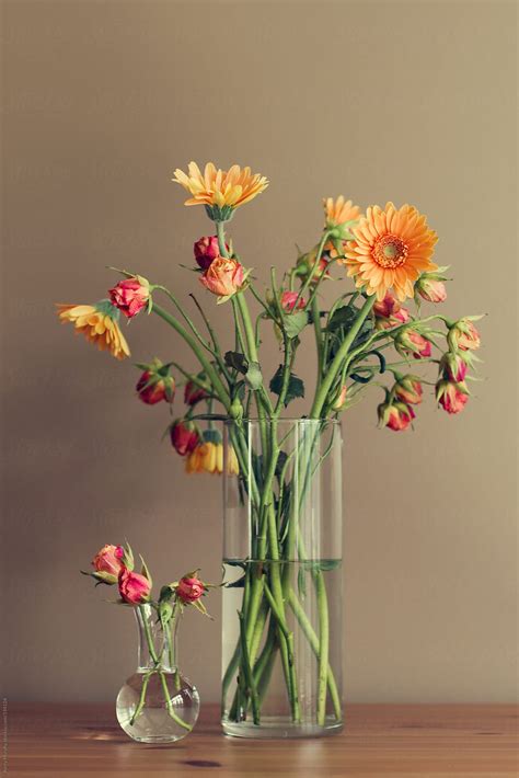 Two Vases Of Gerbera Daisy And Rose Flowers On Wooden Table By