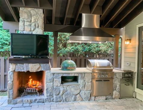 an outdoor kitchen with grill and television