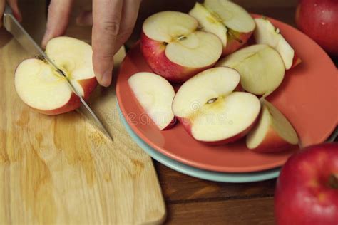 La Mano Corta La Mitad De La Manzana En La Tabla De Corte Imagen De