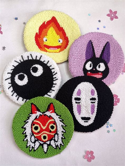 Four Embroidered Badges With Faces On Them Sitting On A Tablecloth