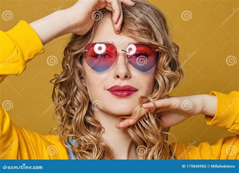 Young Beautiful Woman In Heart Sunglasses On Vivid Yellow Background