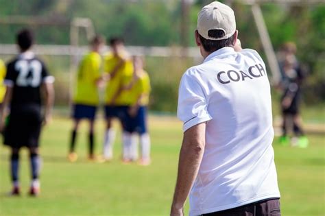 Entrenador de fútbol vistiendo una camiseta blanca de coach en un campo