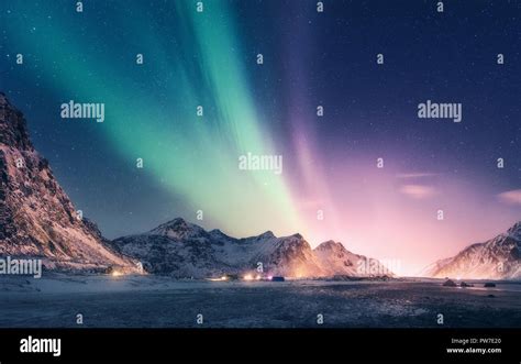 Green and purple aurora borealis over snowy mountains. Northern lights in Lofoten islands ...