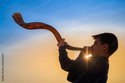 Teen boy blowing Shofar - ram's horn traditionally used for Jewish religious purposes, including ...