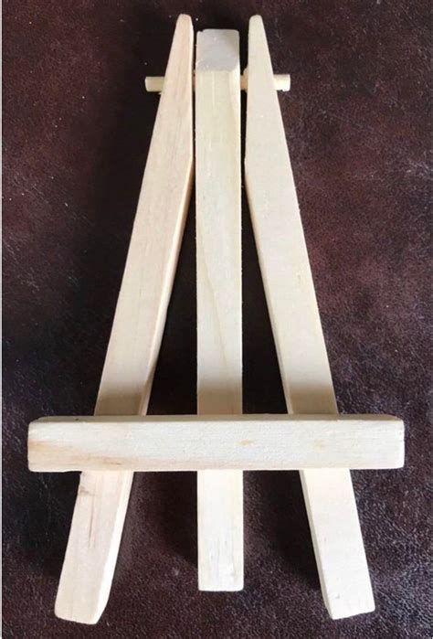 A Small Wooden Easel Sitting On Top Of A Brown Floor Next To A Wall