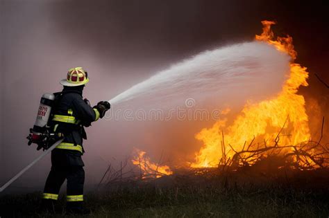 Firefighter Fighting Large Blaze Shooting Water To Extinguish Flames