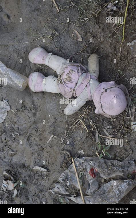 Abandoned Old Broken Baby Doll Rots In Muddy Surface Distress Forlorn