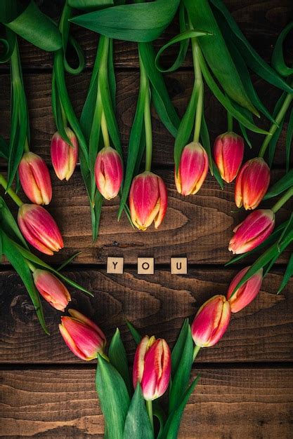 Tulipas cor de rosa estão deitadas em uma mesa de madeira em forma de