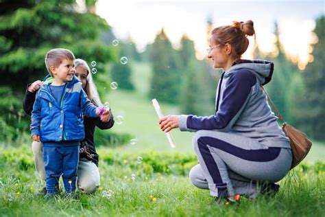 Madre juega con su hija y su hijo en pompas de jabón en un bosque