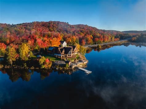 Premium Photo A House On A Lake Surrounded By Trees With Fall Colors