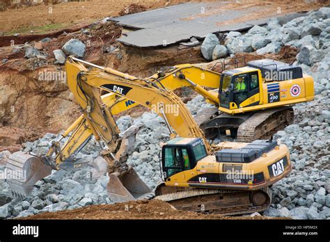 Heavy Equipment Operators Move Stone To Shore Up The Eroded Hillside To