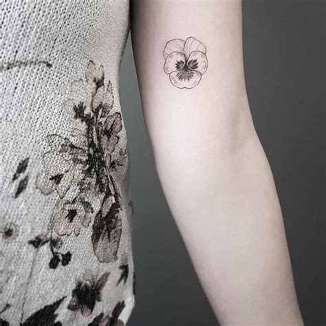 A Woman S Arm With A Small Flower Tattoo On The Left Side Of Her Arm