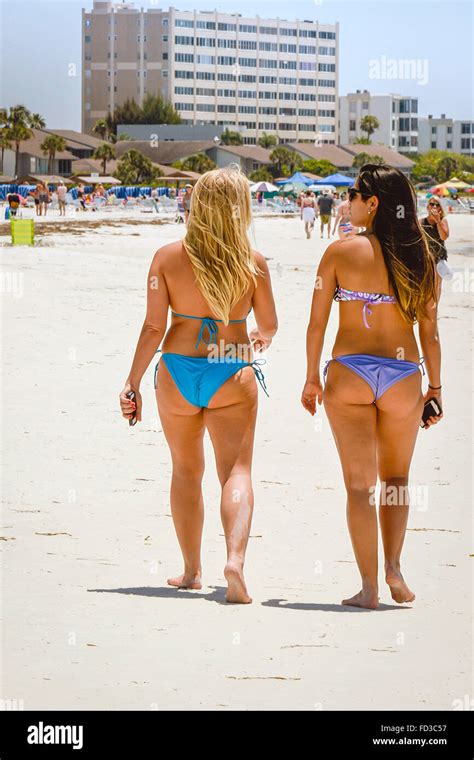 Rear View Of Two Long Haired Blonde And Brunette Women Strolling Beach