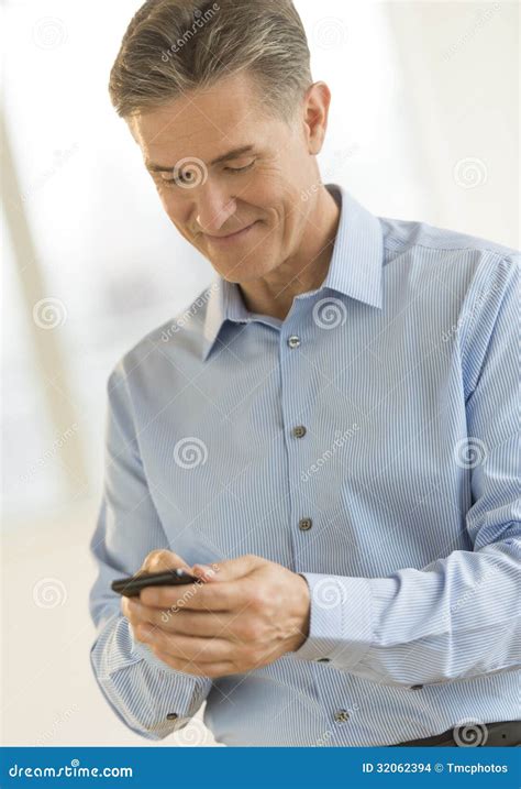 Businessman Smiling While Text Messaging Through Smart Phone Stock