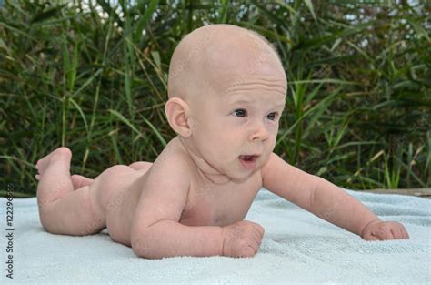 Baby nackt auf dem Bauch liegend Arm abgestützt neugierig blickend