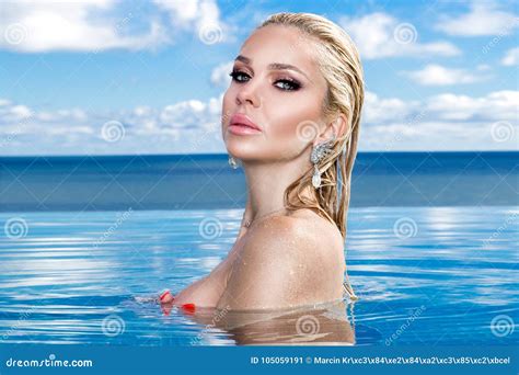 Beautiful Blonde Woman Model With Long Wet Hair And Elegant Makeup Lies In A Pool Stock Image