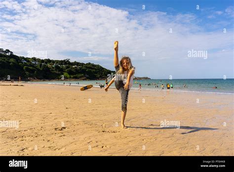 Eine hübsche kleine blonde Mädchen übt ihre Tanz und Gymnastik am Strand tun Splits stehend
