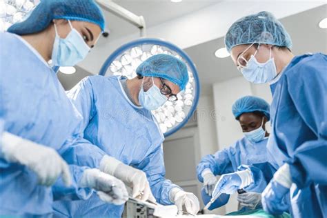 Diverse Team Of Professional Surgeon Assistants And Nurses Performing Invasive Surgery On A