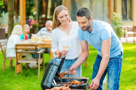 Parrillada Familiar Feliz Pareja Joven Asando Carne A La Parrilla