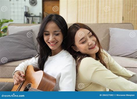 LGBTQIA Lesbian Gay Couple Playing Guitar And Singing With Romantic Feelings At Home Stock Photo