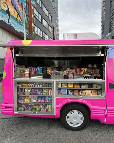 A Pink Food Truck Parked In Front Of A Tall Building With Lots Of Books