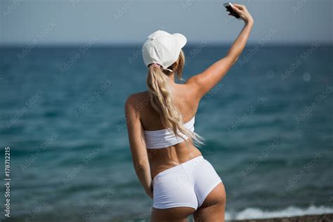 Foto De Beautiful Blonde Girl In Sportwear On The Beach Makes Selfie Do Stock Adobe Stock