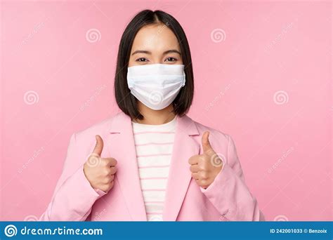 Asian Businesswoman In Suit And Medical Face Mask Showing Thumbs Up