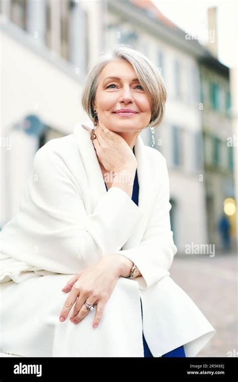 Outdoor Portrait Of Beautiful And Elegant Middle Age 55 60 Year Old Woman Wearing White