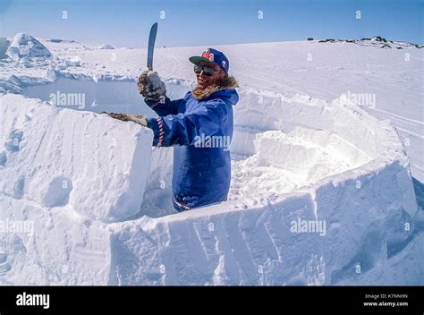 Inuit elder man, dressed in modern arctic clothing, builds igloo by ...