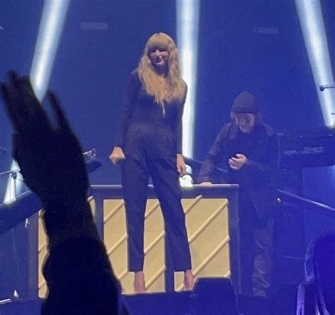 a woman standing on top of a stage in front of a man holding his hand up