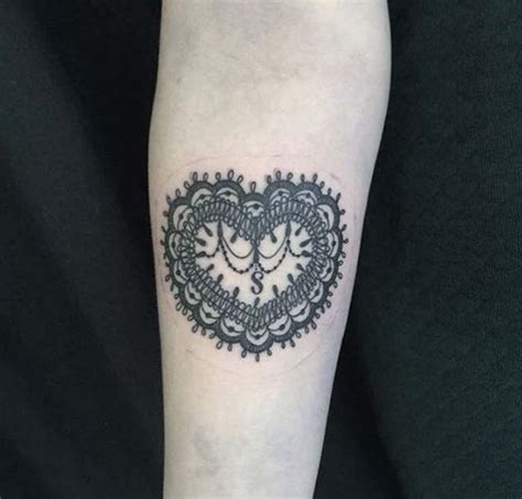 Ornamental style black and white heart shaped tattoo on forearm area ...