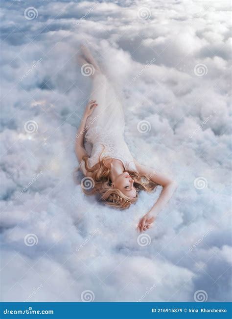 Young Beautiful Happy Blonde Woman Lies In Soft Bed On White Clouds In