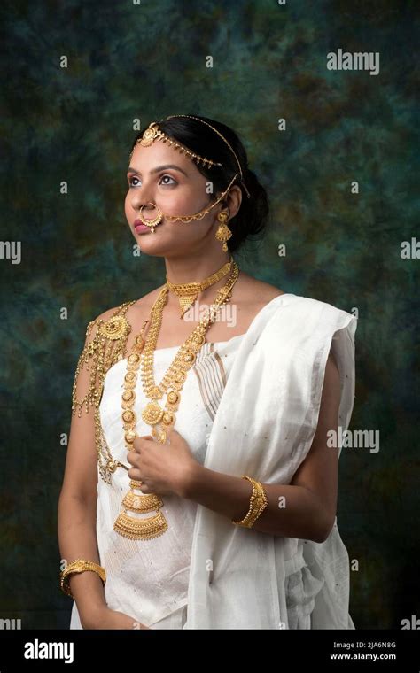 Indian Female Model Wearing A White Saree And Gold Jewellry Sporting A