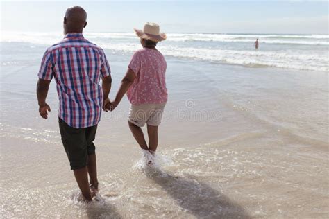 Pareja Afroamericana De Tercera Edad Con La Mano Caminando En La Playa