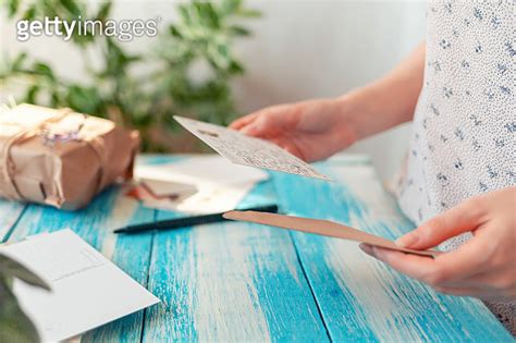 A Female Hands Holding A Postcard And Envelope Close Up Blue Wooden